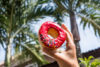 Holding donut near palm trees
